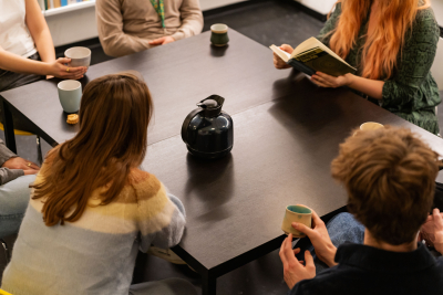 mennesker samlet rundt om et bord med bog og kaffekopper