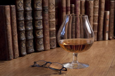 Et par briller, der ligger ved siden af et glas whisky